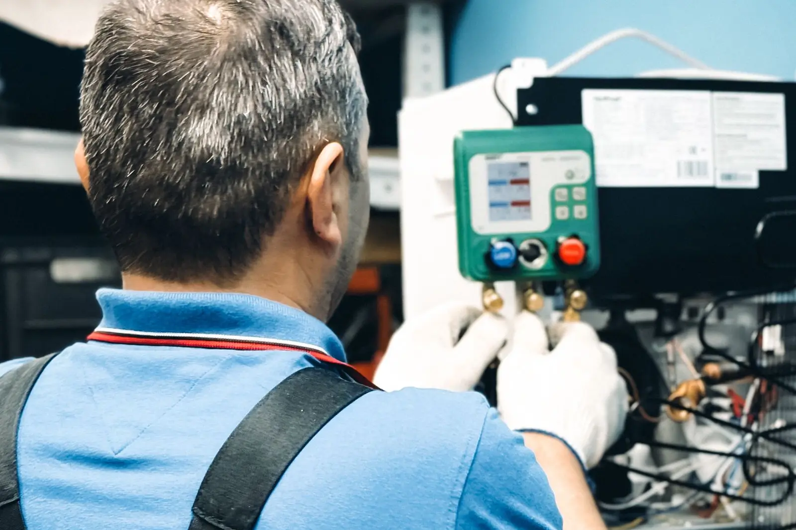 Technician reading refrigerant gauges during AC maintenance